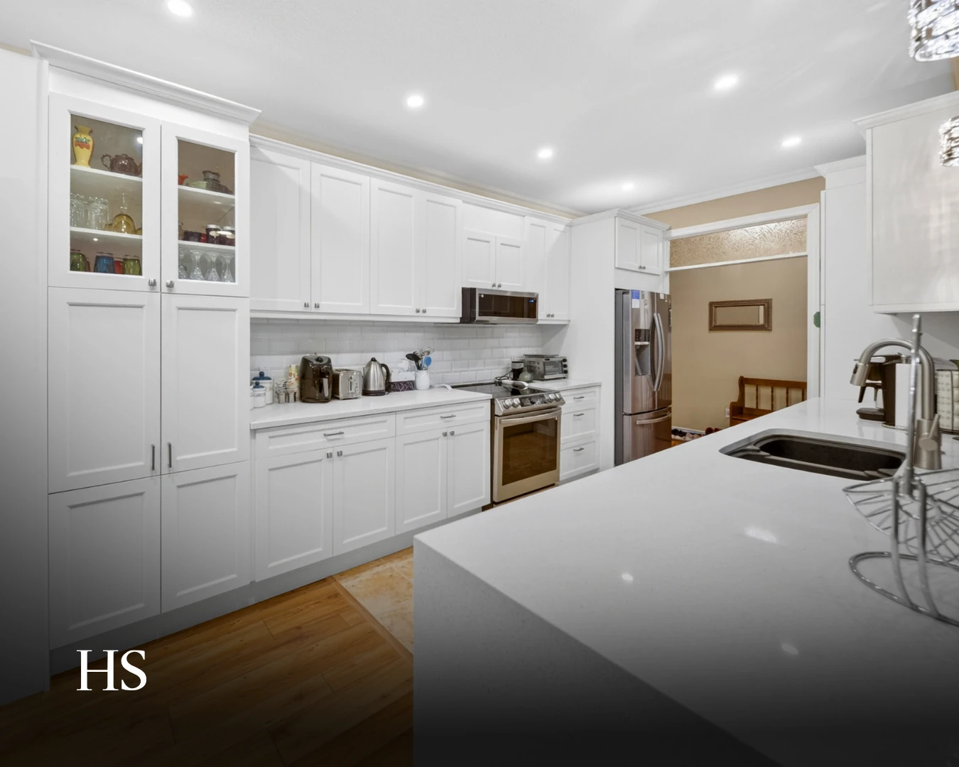 White shaker kitchen with a quartz island and a glass-front display cabinet