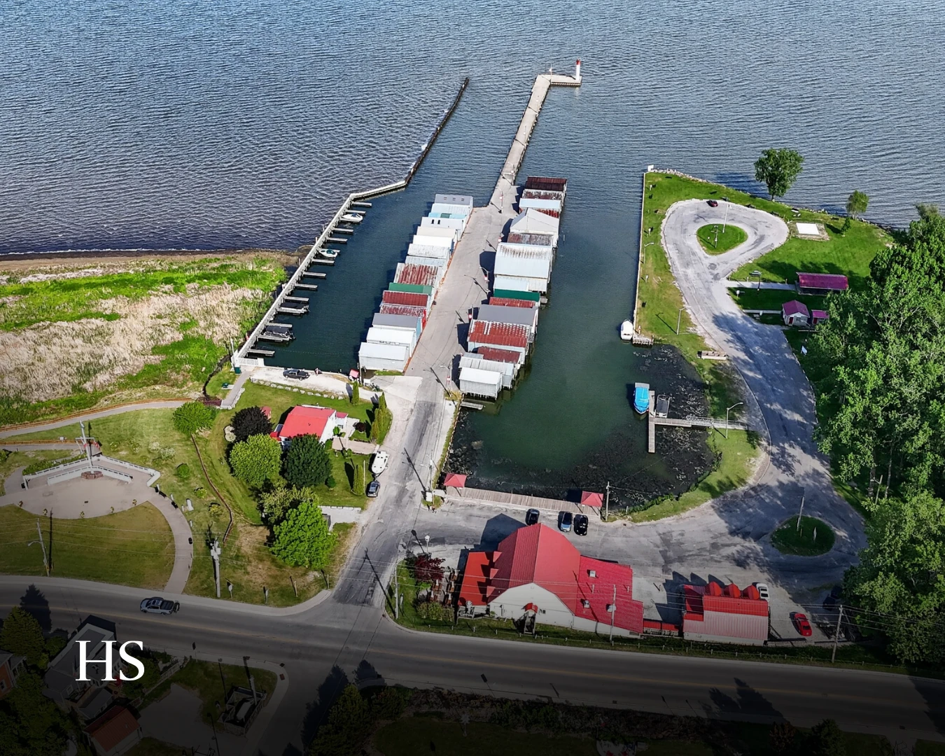 Drone aerial of the harbour, its docks and moored boats, with the shoreline park below