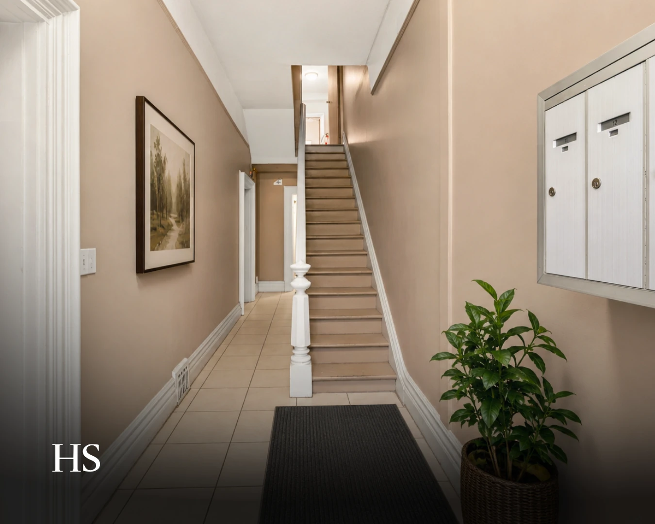 Interior hallway with a carpeted staircase, white balustrade and framed art