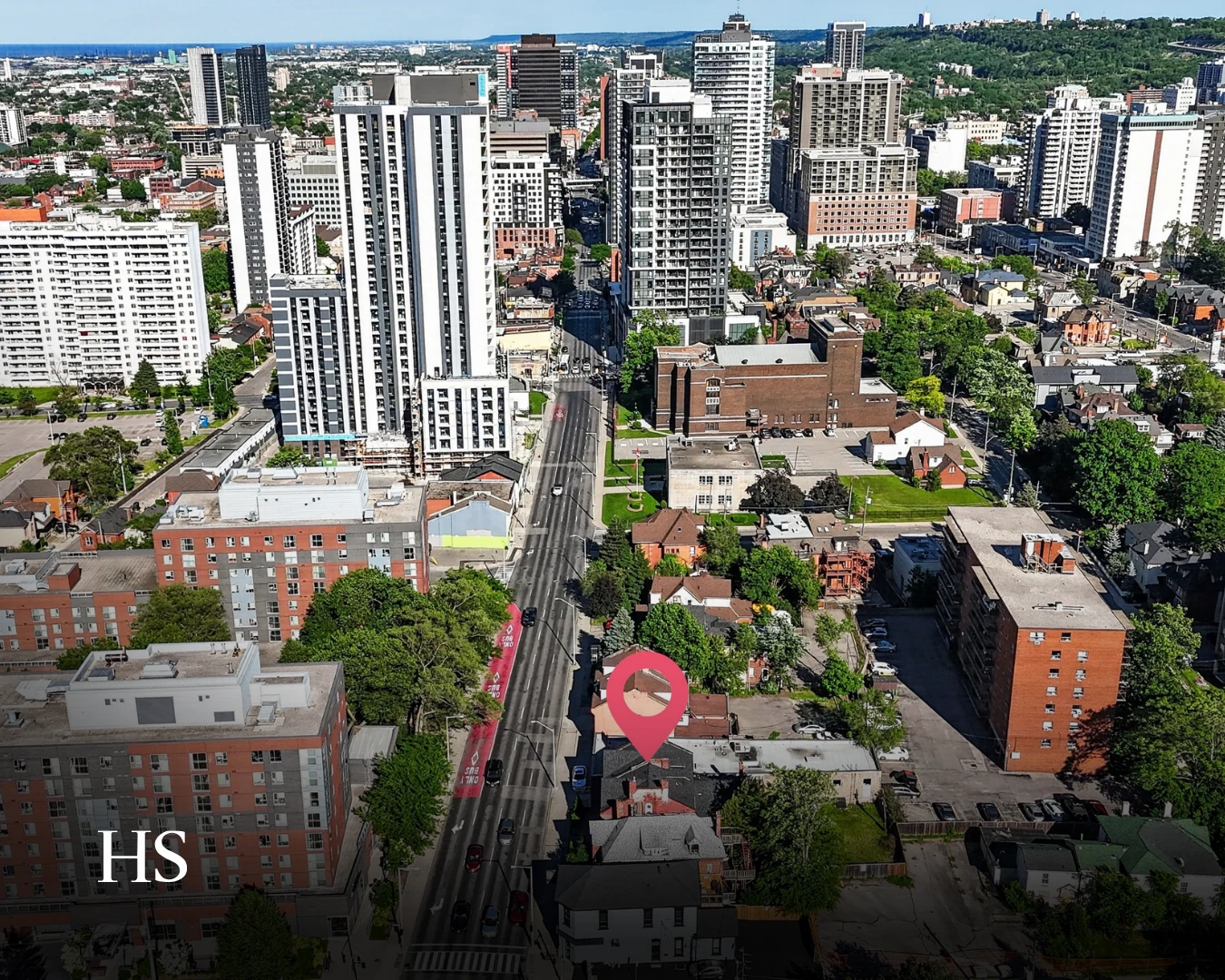 Downtown Hamilton aerial with a red map-pin graphic marking the property, the escarpment and Lake Ontario at the horizon