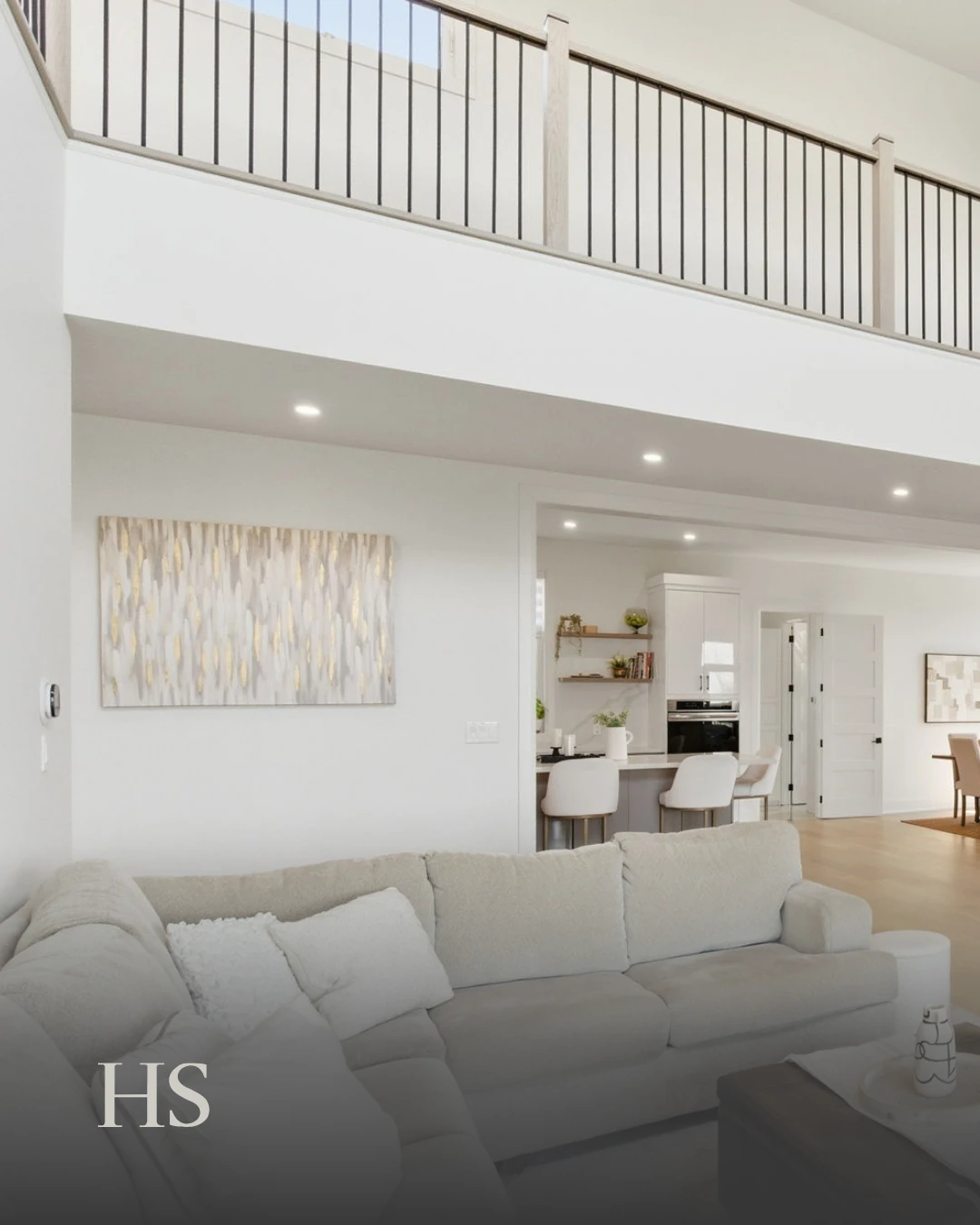 Double-height living room with a pale sectional and black-framed windows above