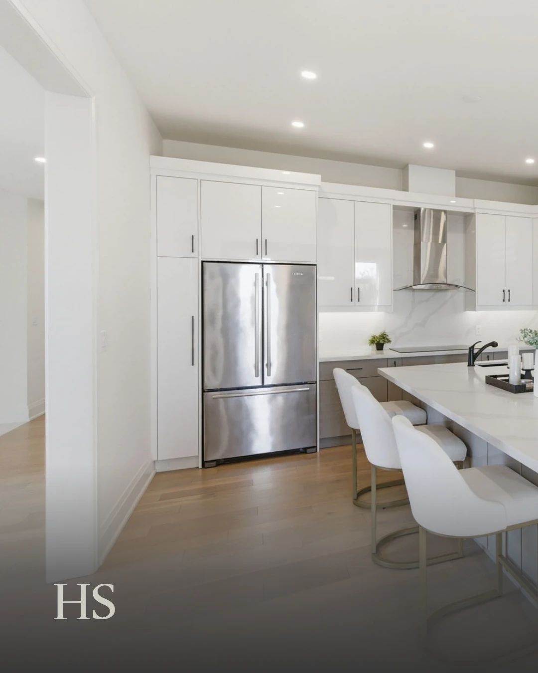 White kitchen with tall cabinetry, a marble backsplash, a quartz island and leather bar stools