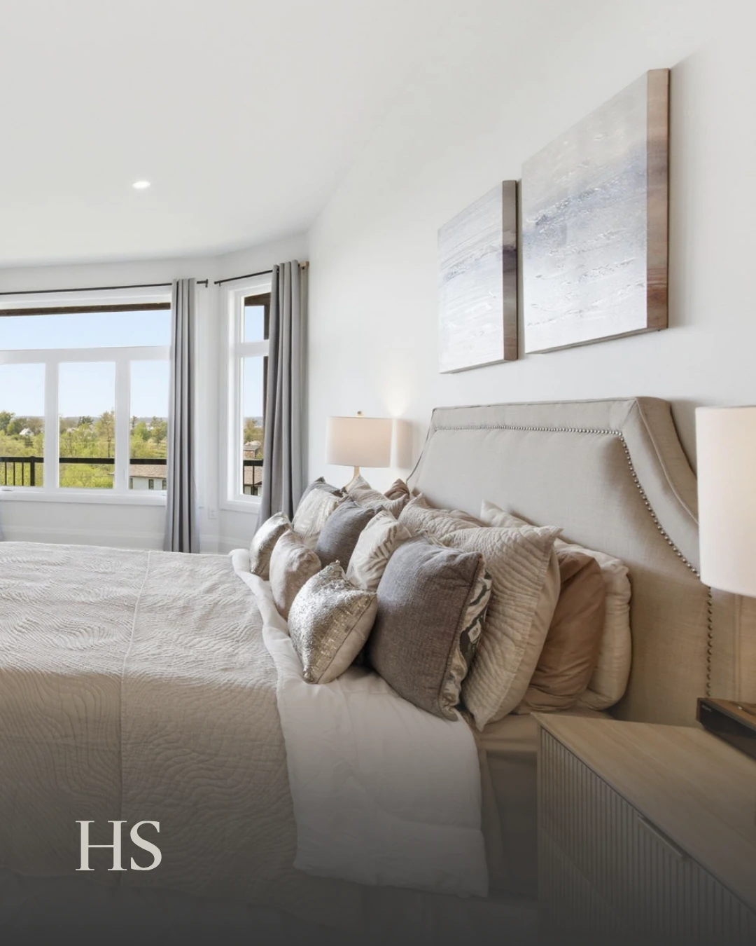 Bedroom with a panelled headboard, beige bedding, a bench and artwork above