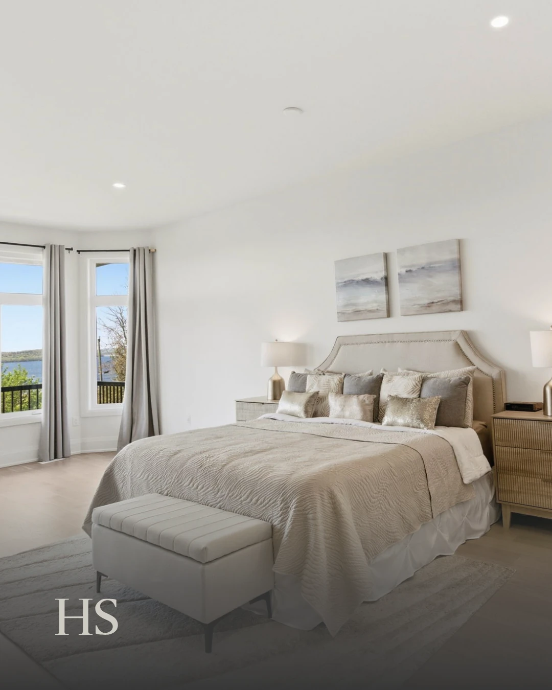 Primary bedroom with a white bench at the foot and a Rice Lake view through the window