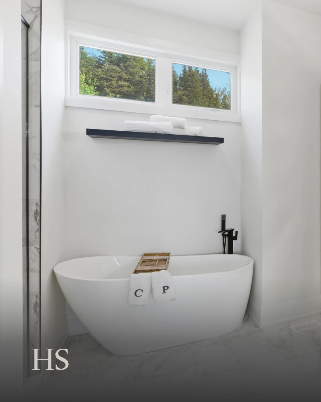 Bathroom with a freestanding tub on grey floor tile beneath a window