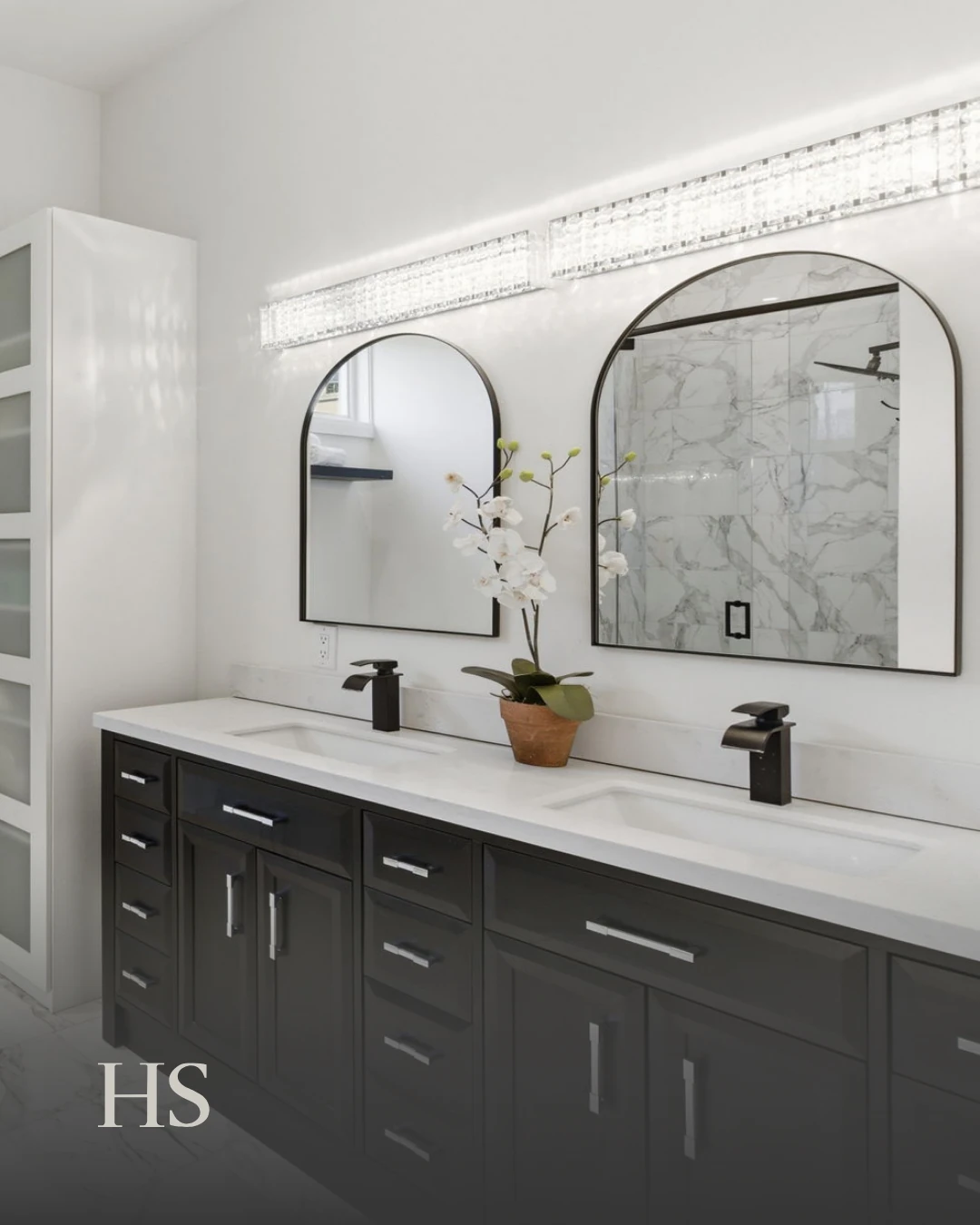 Bathroom with twin arched mirrors above a dark vanity and a marble-topped counter