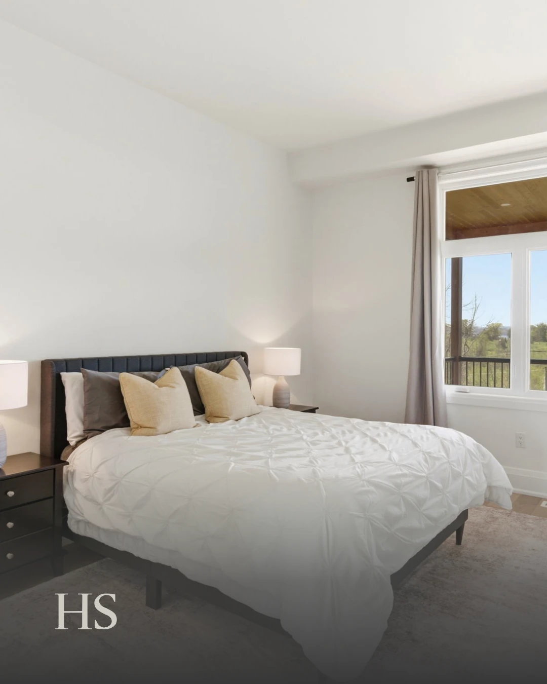 Bedroom with a dark bed frame and white bedding, opening onto the deck