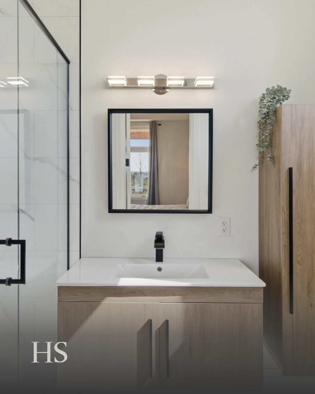 Bathroom with a glass shower enclosure and a wood vanity beneath a framed mirror