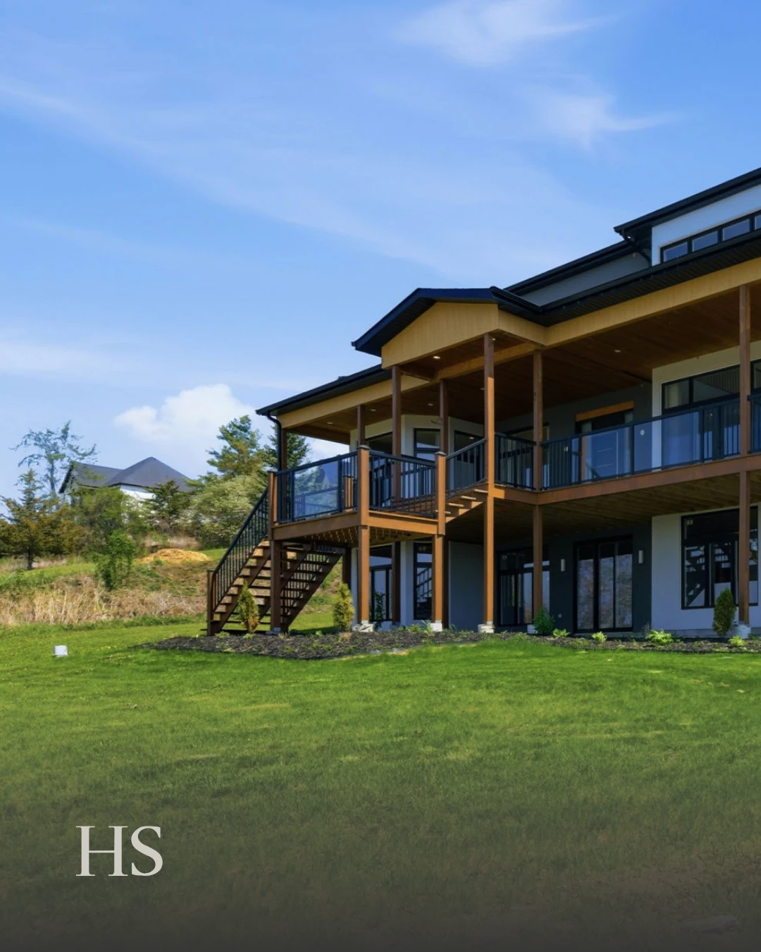 Exterior of the charcoal multi-level home showing its stacked wood balconies above the lawn