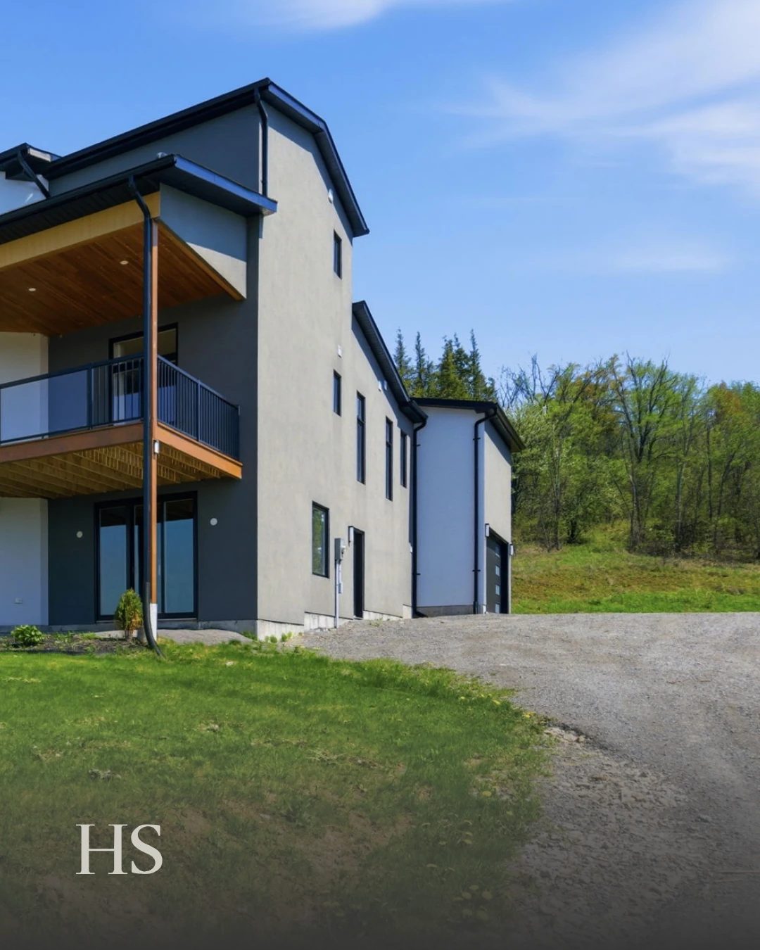 Side elevation of the charcoal house on its slope beside a gravel drive