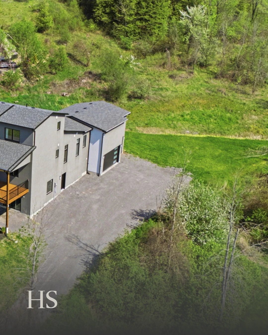 Drone aerial of the rear of the house and its long driveway through the trees