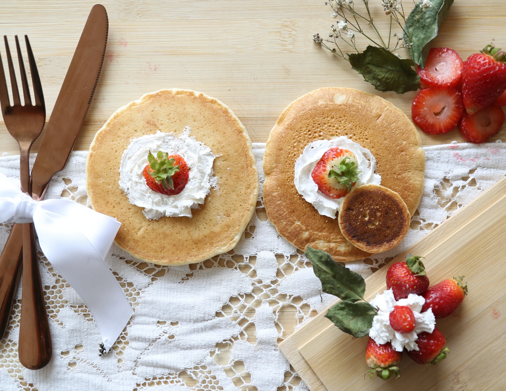 Raw pancake photograph with ribbon-tied cutlery and a strawberry garnish