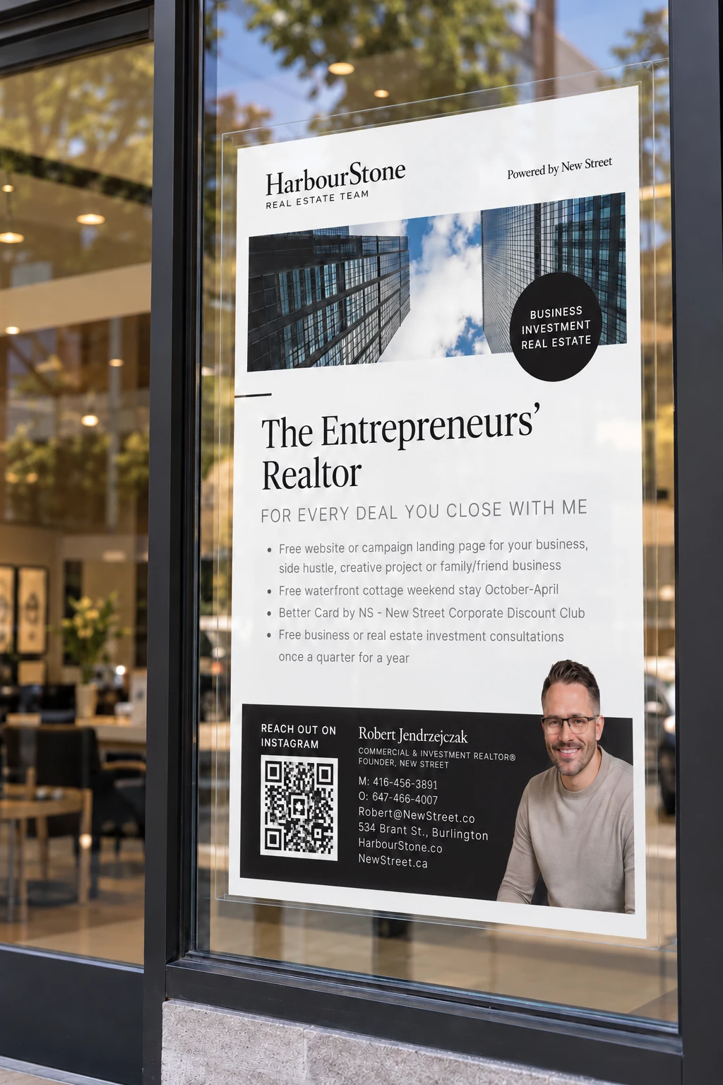 Robert Jendrzejczak's print behind an office window — glass-tower photos above "The Entrepreneurs' Realtor" and a black contact block