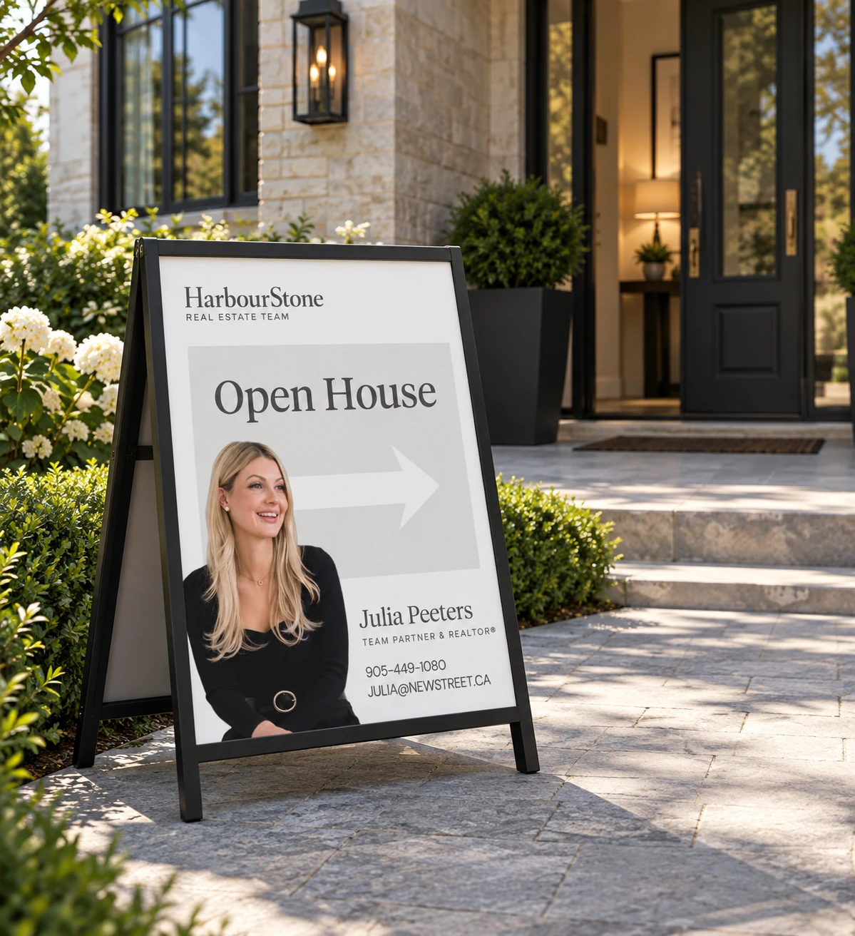 Black A-frame Open House board on a front path — "Open House", a right-pointing arrow, and Julia Peeters' photograph and contact block